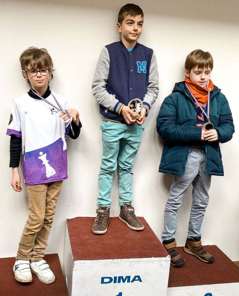 Trois enfants sur un podium après une compétition d'échecs